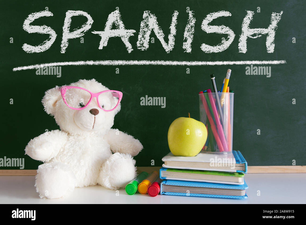 Hand schreiben auf einer Tafel in einer Klasse mit dem Wort "Spanisch" schrieb. Einige Bücher und Schulmaterial in einem Kind im Klassenzimmer. Stockfoto