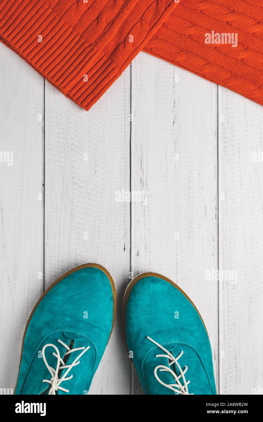 Fashion Concept, Ansicht von oben. Casual Lifestyle im Herbst. Flach. Grüne Frauen Schuhe und roten Strickpullover auf weißem Holz Hintergrund. Stockfoto