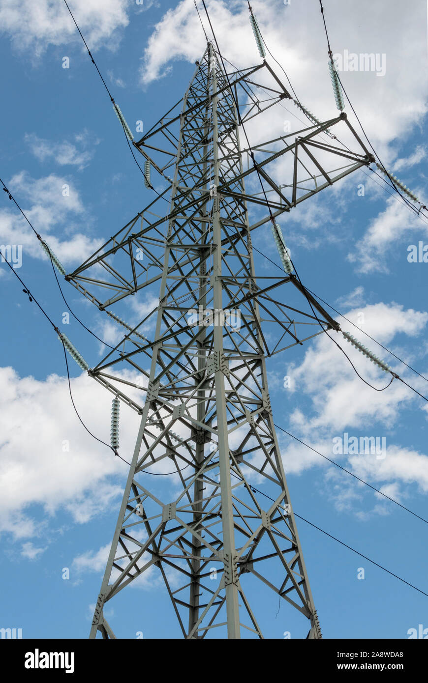 Hochspannungs-elektrische Kraftübertragung und niedrige Winkel Ansicht der Hochspannungsleitungen Tower-Mast gegen blauen Himmel und weißen Wolken. Stockfoto