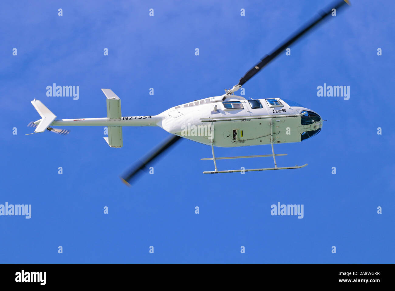 Bell JetRanger 206 Hubschrauber N 27554 flying Overhead, vor blauem Himmel Hintergrund Stockfoto