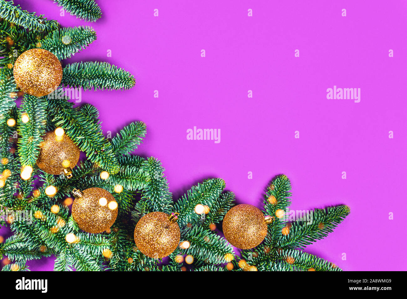 Weihnachtskarte mit Fir brunches, goldene Kugeln und Lichtern auf lila Hintergrund. Flach, Ansicht von oben, kopieren. Stockfoto