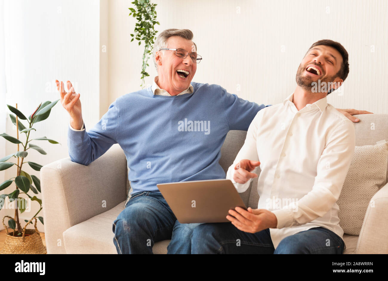 Middle-Aged Sohn und Vater mit Laptop Lachen zu Hause Stockfoto