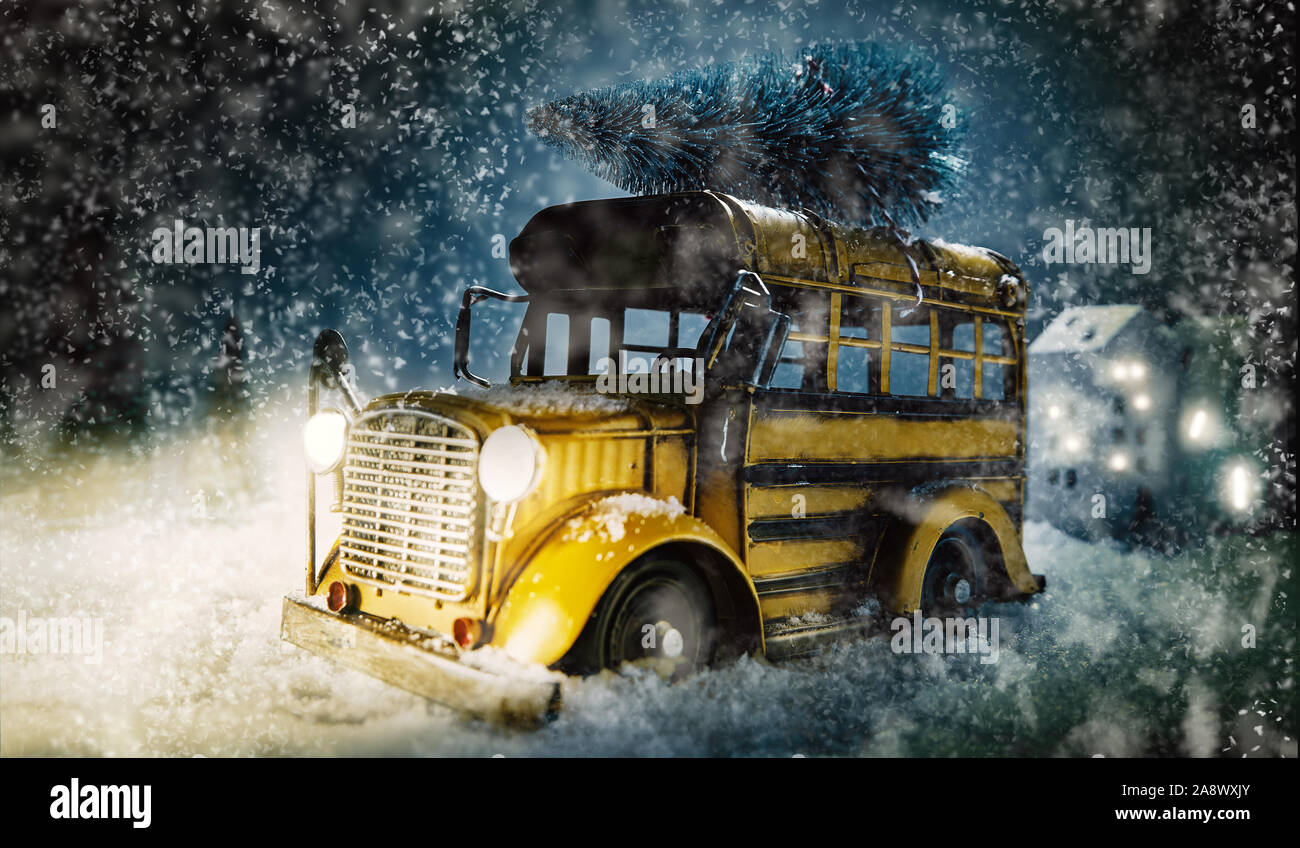 Bunte vintage gelben Bus mit Weihnachtsbaum auf dem Dach durch fallende Schnee in einem Dorf mit Scheinwerfer leuchten und Raum für Ihre Kopie Stockfoto