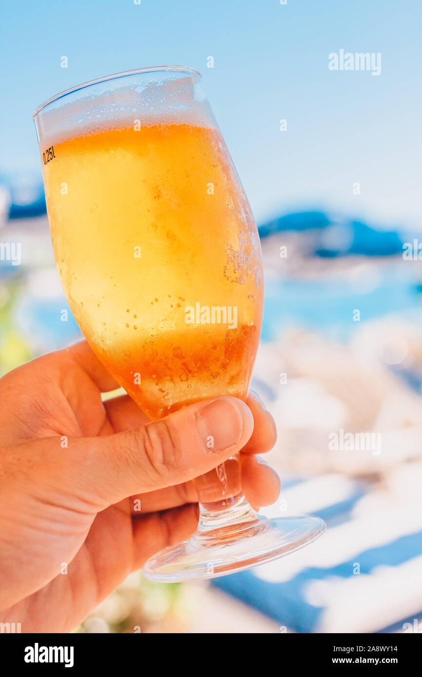 Ein Glas kaltes Bier in der Hand gegen den blauen Himmel Stockfoto