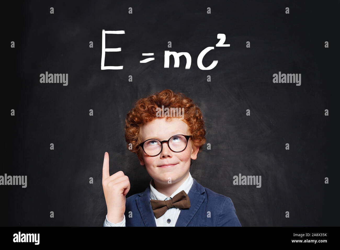 Gerne neugierig Kid little boy Genius auf blackboard Hintergrund Stockfoto