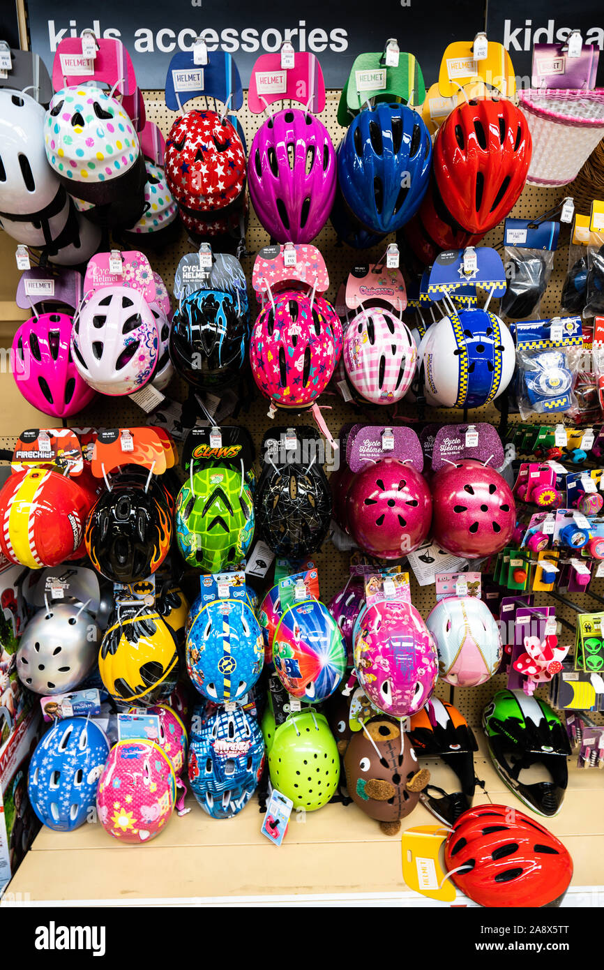 Kinder und Erwachsene Radfahren, Skaten und Skaten Schutzhelme zum Verkauf an der lokalen Halfords Store auf der Hohe Straße in der Stadt Stockfoto