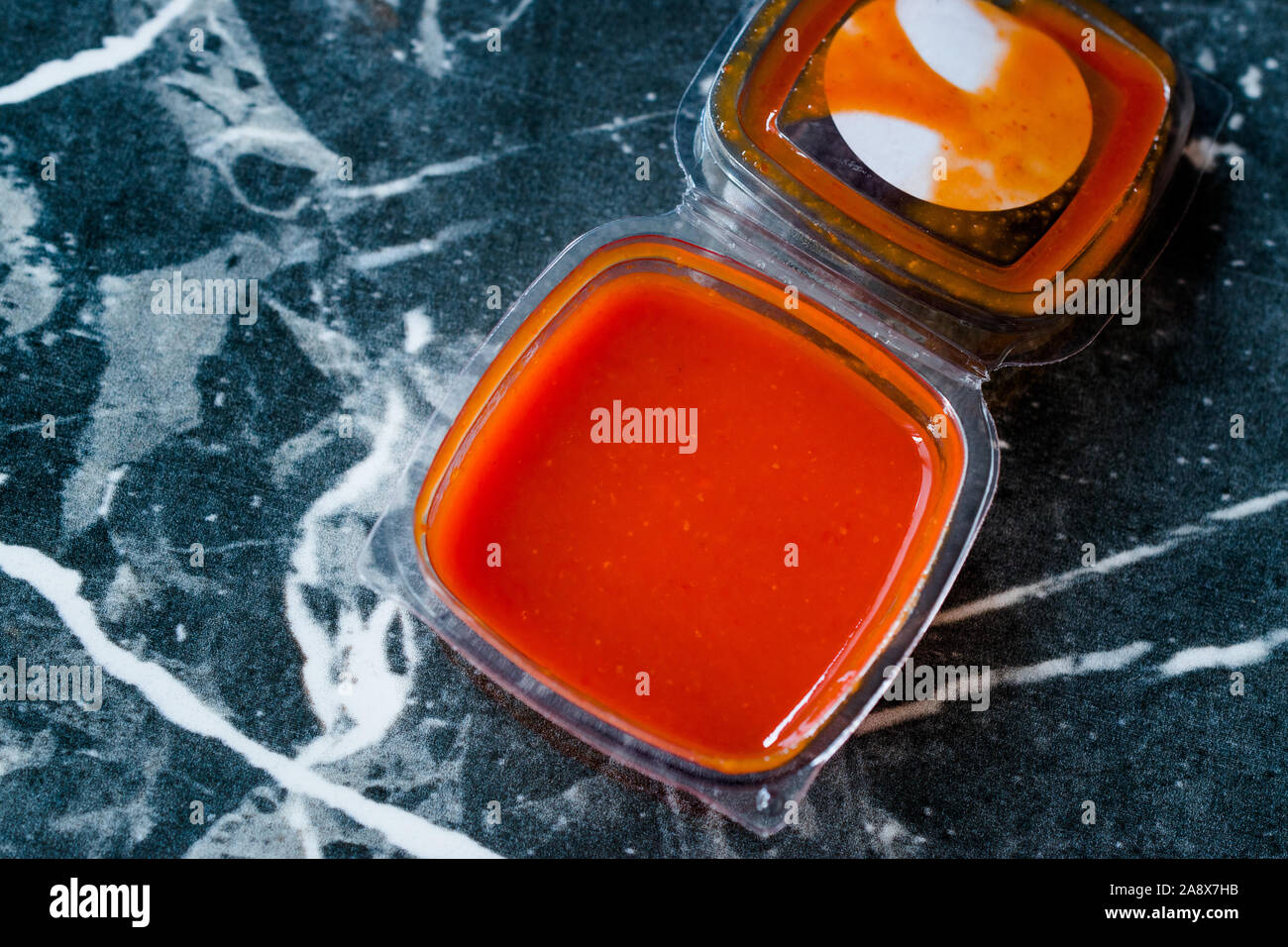 Hot Scharfe rote Sriracha Soße in Plastik Box/Paket oder Behälter für Fast Food bereit zu essen. Traditionelle Speisen Soße. Stockfoto