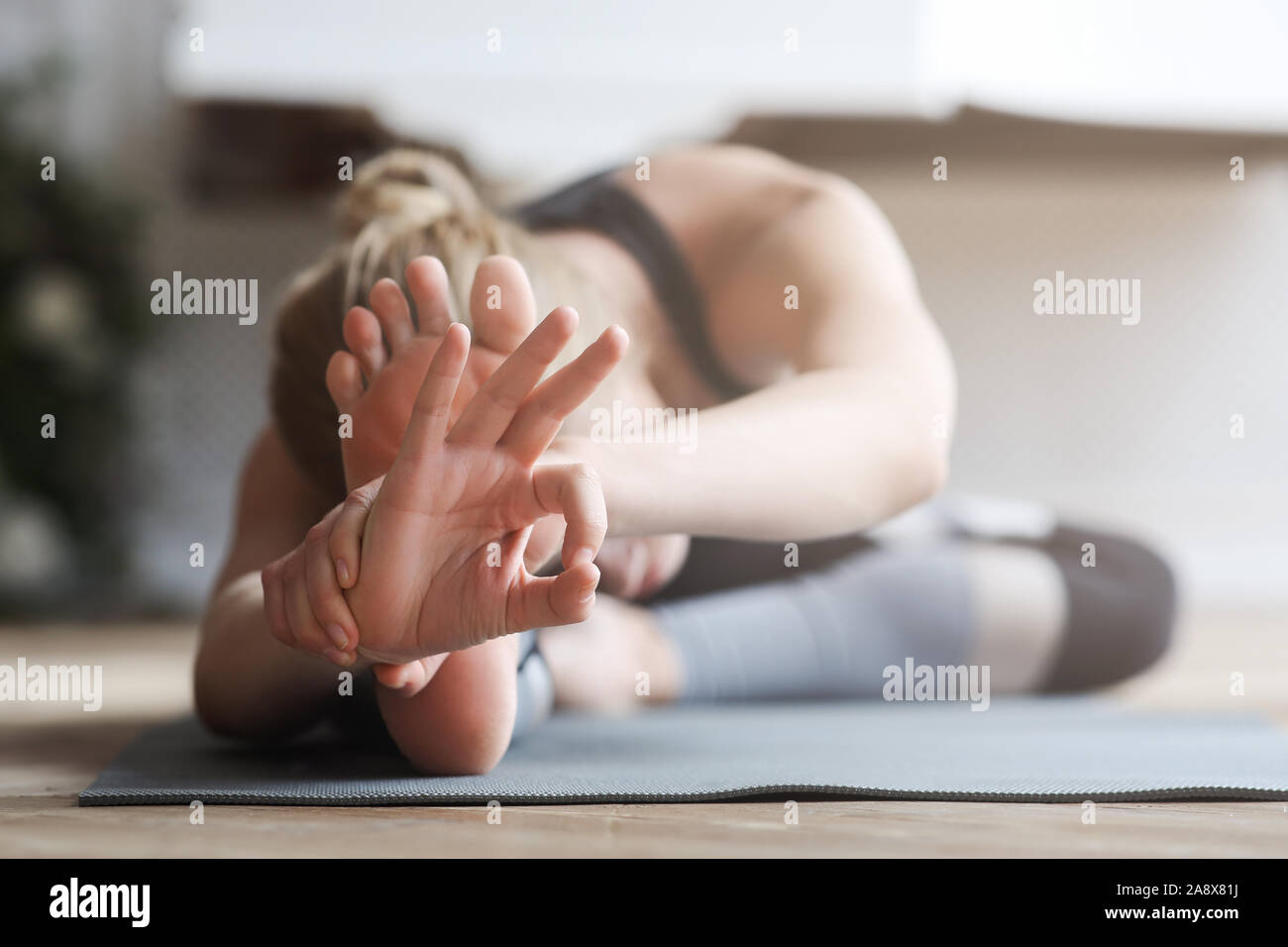 Flexible girl Stretching zu Hause, Ihre Knie berühren mit der Stirn Stockfoto