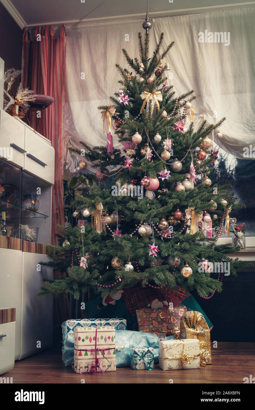 Es ist die Heilige Nacht, die geschmückten Weihnachtsbaum im Wohnzimmer und unten sind die aufgewickelte Weihnachtsgeschenke. Authentisches Bild der eigenen Partei. Stockfoto