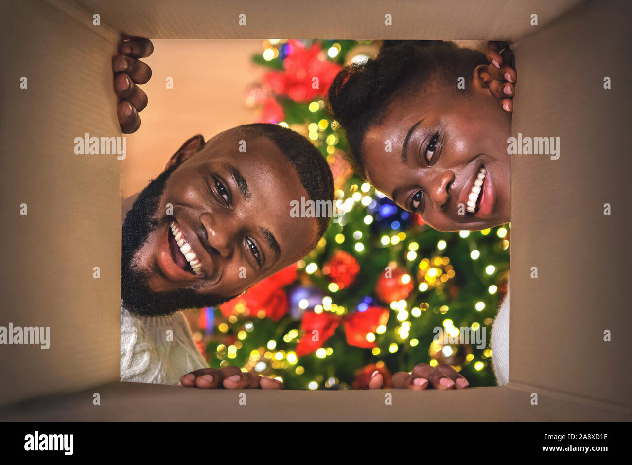 Aufgeregt afro Paar öffnen Weihnachtsgeschenk zu Hause Stockfoto