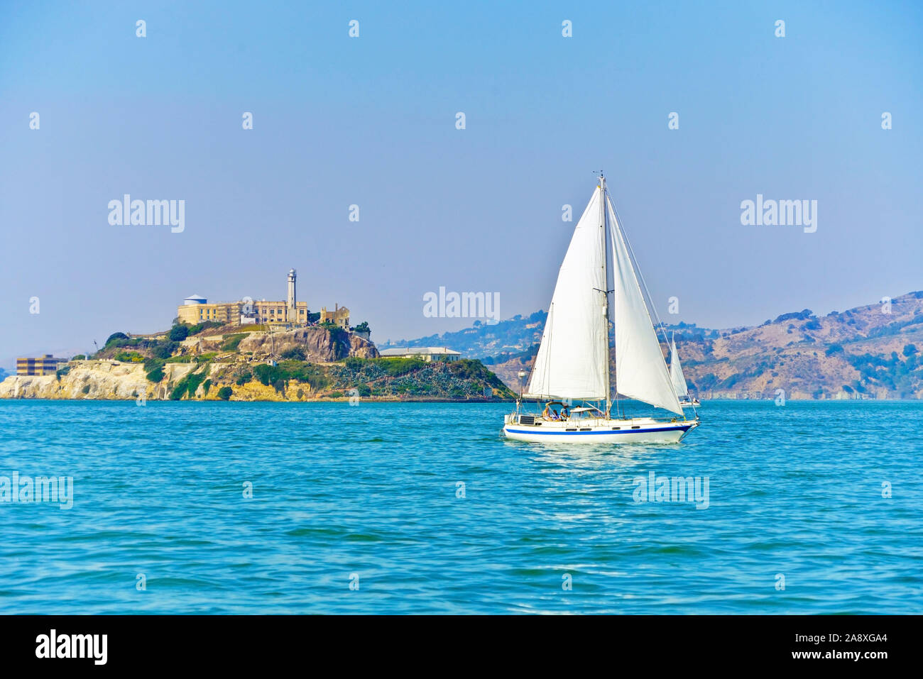 Blick auf Alcatraz Island mit einem segelboot, das an der San Francisco Bay in San Francisco vorbeiführt. Stockfoto