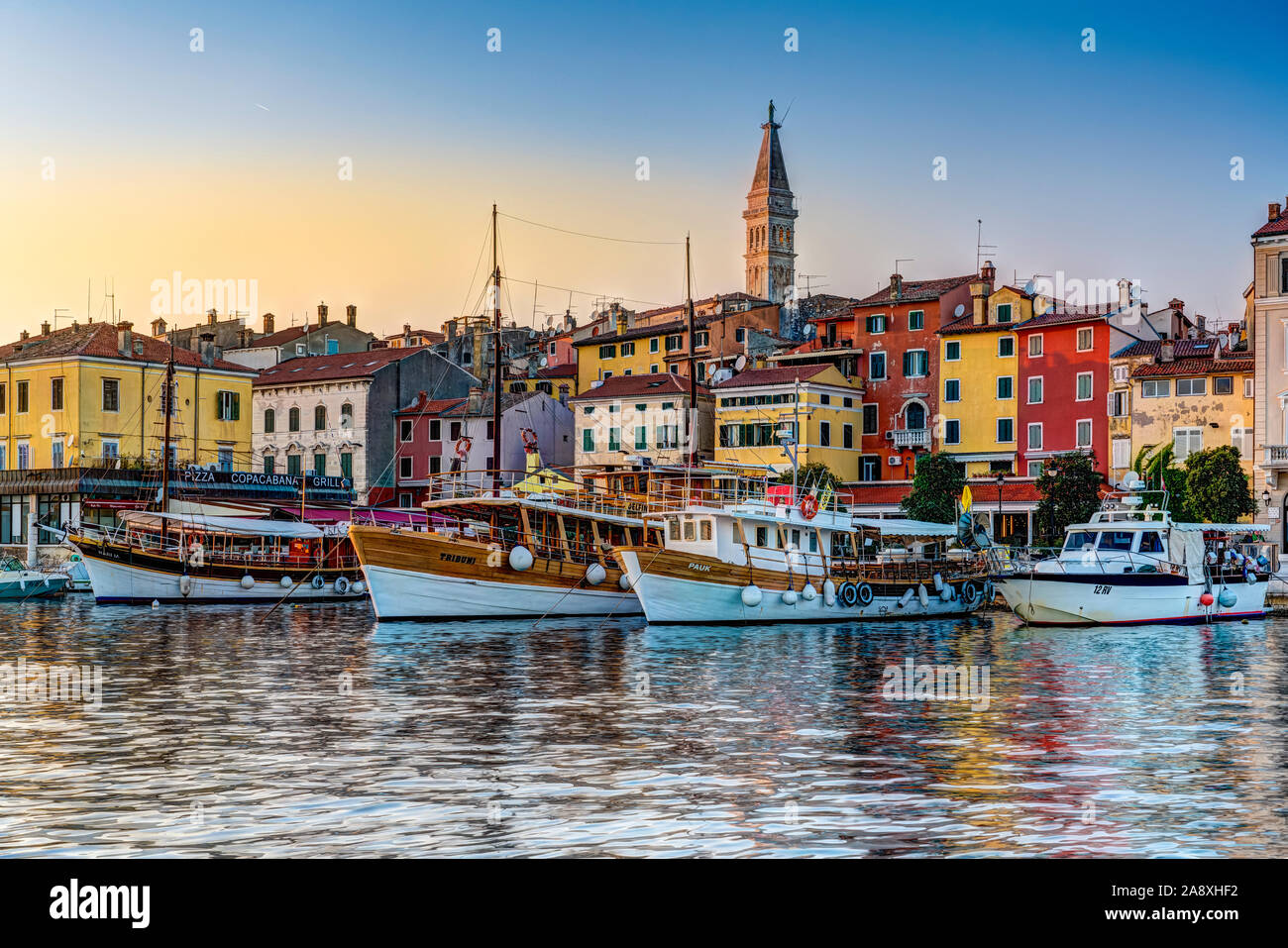 Farbenfrohe Gebäude und das Dorf Skyline bei Sonnenuntergang mit Vergnügen und Fischerboote in Rovinj, Kroatien, Istrien. Stockfoto