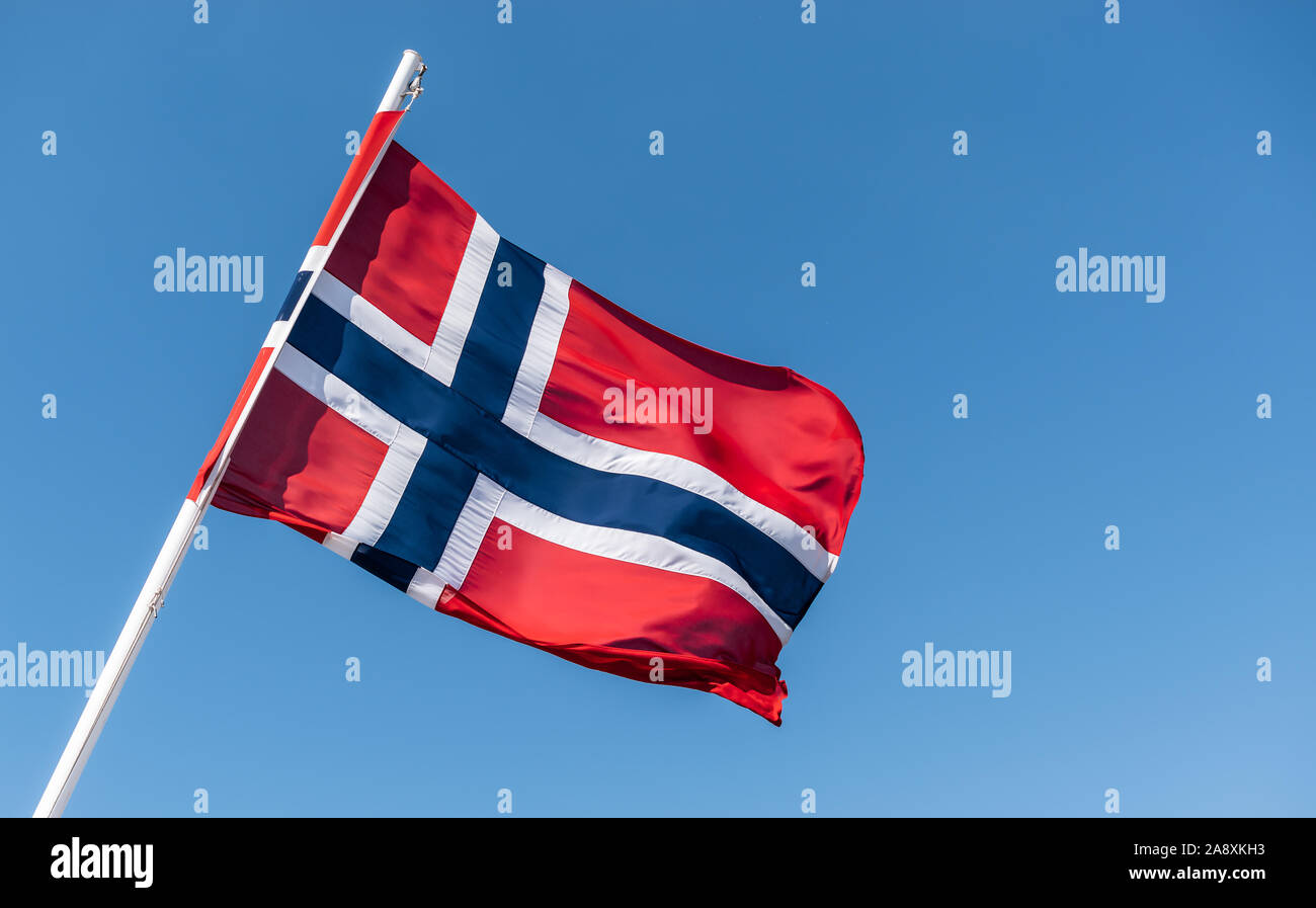 Flagge Norwegen. Norwegische Flagge auf Fahnenmast winken im Wind gegen den blauen Himmel. Stockfoto