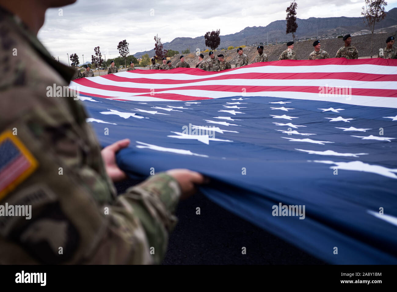 El Paso, Texas, USA. 11 Nov, 2019. Soldaten des 1.Bataillon, 77. Armor Regiment, 3. gepanzerte Brigade Combat Team 'Bulldogge'', 1st Armored Division, eine amerikanische Flagge während der Feier ist ein Veteran in El Paso, Texas. Quelle: Joel Engel Juarez/ZUMA Draht/Alamy leben Nachrichten Stockfoto