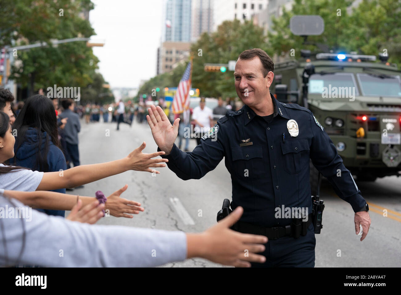 Austin assistant Police Chief Troy Gay grüßt die Menge mit High Fives während der jährlichen Veterans Day Parade auf der Congress Avenue in der Innenstadt von Austin. Stockfoto