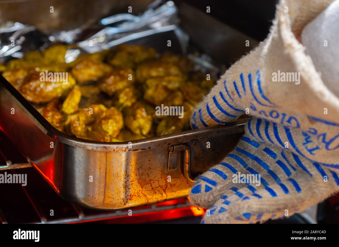 Ein Ofen Mitt Zupacken geröstete Paprika aus der Hitze Stockfoto