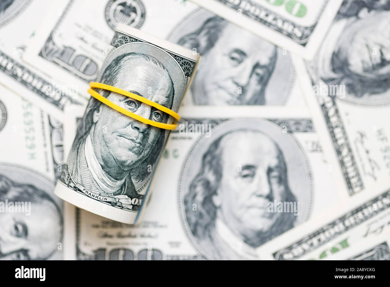 Eine Rolle von 100 Dollar-Scheine close-up auf einem Stapel der Amerikanische Dollar. Von Banknoten von 100 amerikanischen Dollar Hintergrund. Das Finanzkonzept. Stockfoto Eine Rolle von 100 Dollar-Scheine close-up auf einem Stapel der Amerikanische Dollar. Von Banknoten von 100 amerikanischen Dollar Hintergrund. Das Finanzkonzept. Stockfoto