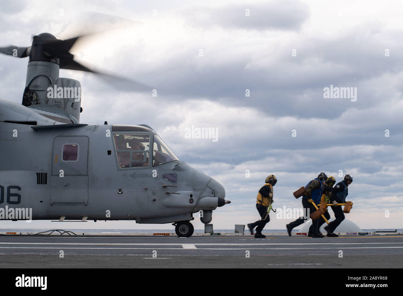 U.S. Navy's Aviation Bootsmann Gehilfen (Handling) Keilen und Ketten von einem MV-22 Osprey, Marine Medium Tiltrotor Squadron (VMM) 263 zugewiesen, da es bereitet aus dem Flight Deck des Flugzeugträgers USS John C Stennis (CVN 74) im Atlantischen Ozean, Nov. 8, 2019. Die John C Stennis unterwegs ist die Durchführung von routinemäßigen Maßnahmen zur Unterstützung der Commander, Naval Air Force Atlantik. (U.S. Marine Foto von Mass Communication Specialist 3. Klasse Jarrod A. Schad) Stockfoto