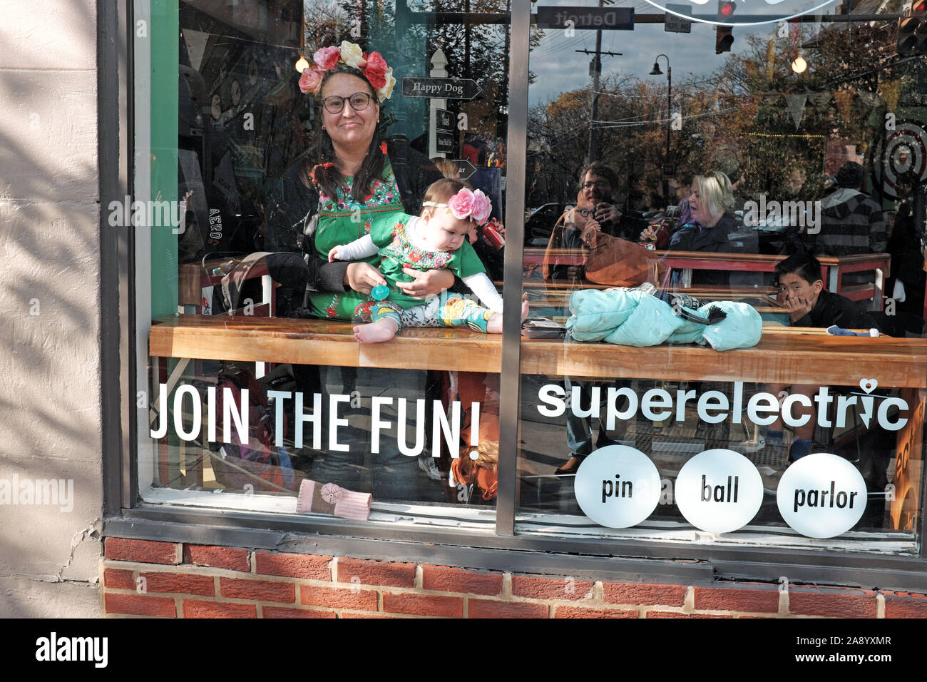 Frau hält ihr Baby im Fenster der Superelectric Pinball Parlour im