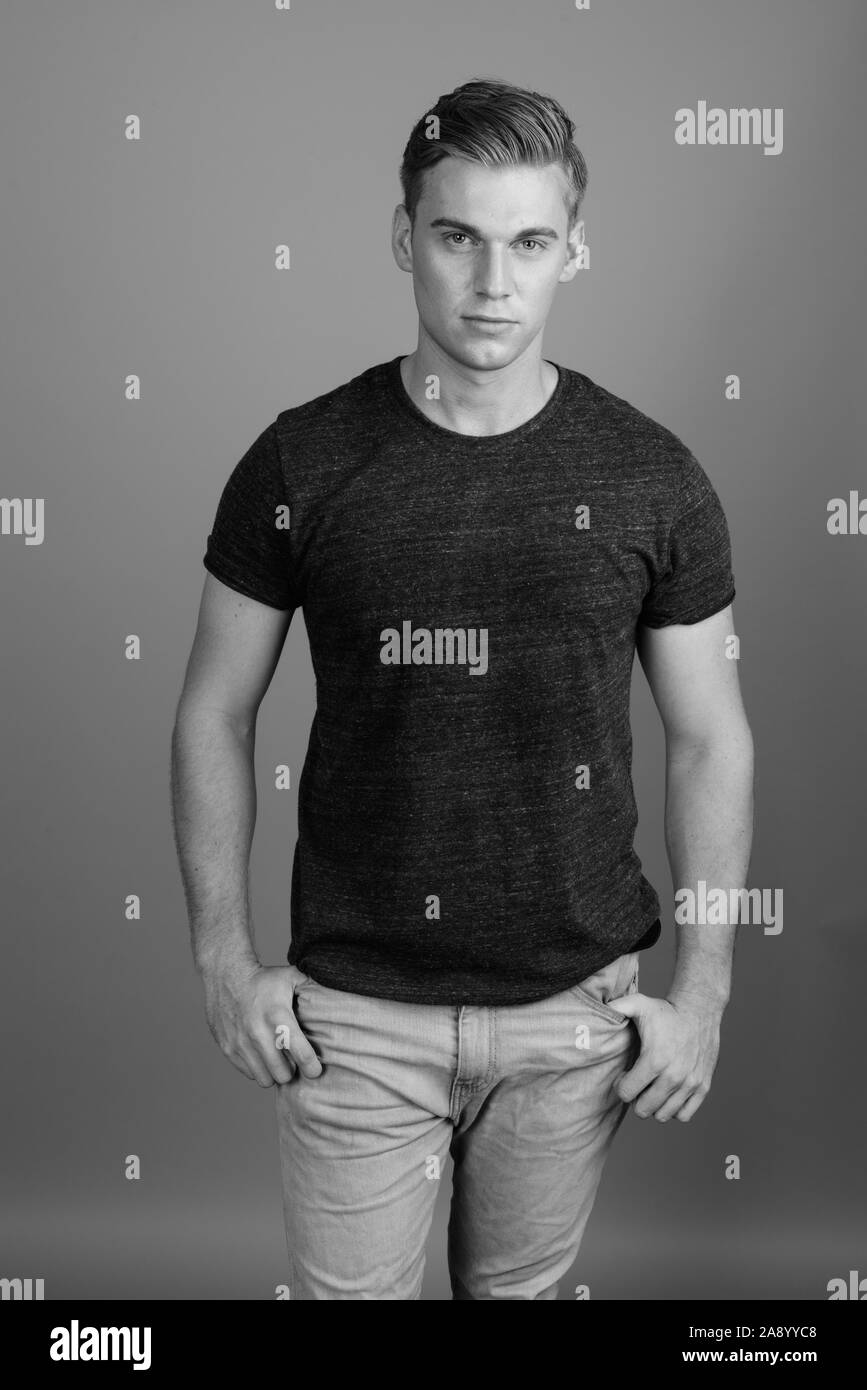 Porträt der jungen gutaussehenden Mann gegen grauen Hintergrund in Schwarz und Weiß Stockfoto