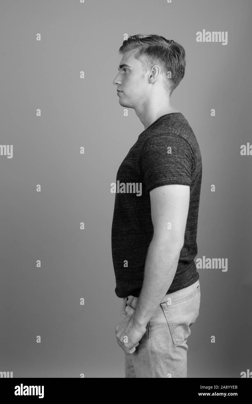 Profil anzeigen von jungen gutaussehenden Mann gegen grauen Hintergrund in Schwarz und Weiß Stockfoto