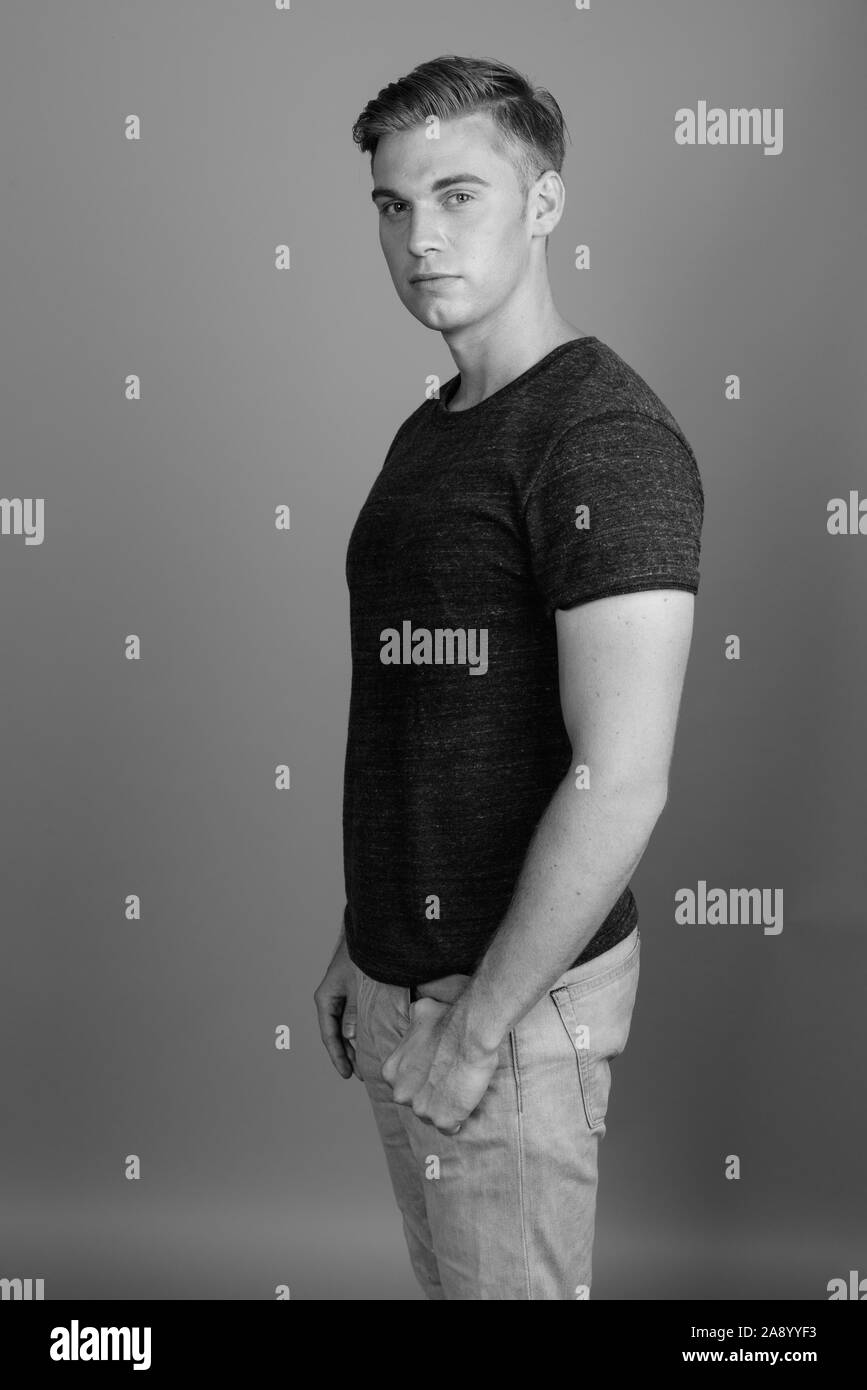 Porträt der jungen gutaussehenden Mann gegen grauen Hintergrund in Schwarz und Weiß Stockfoto