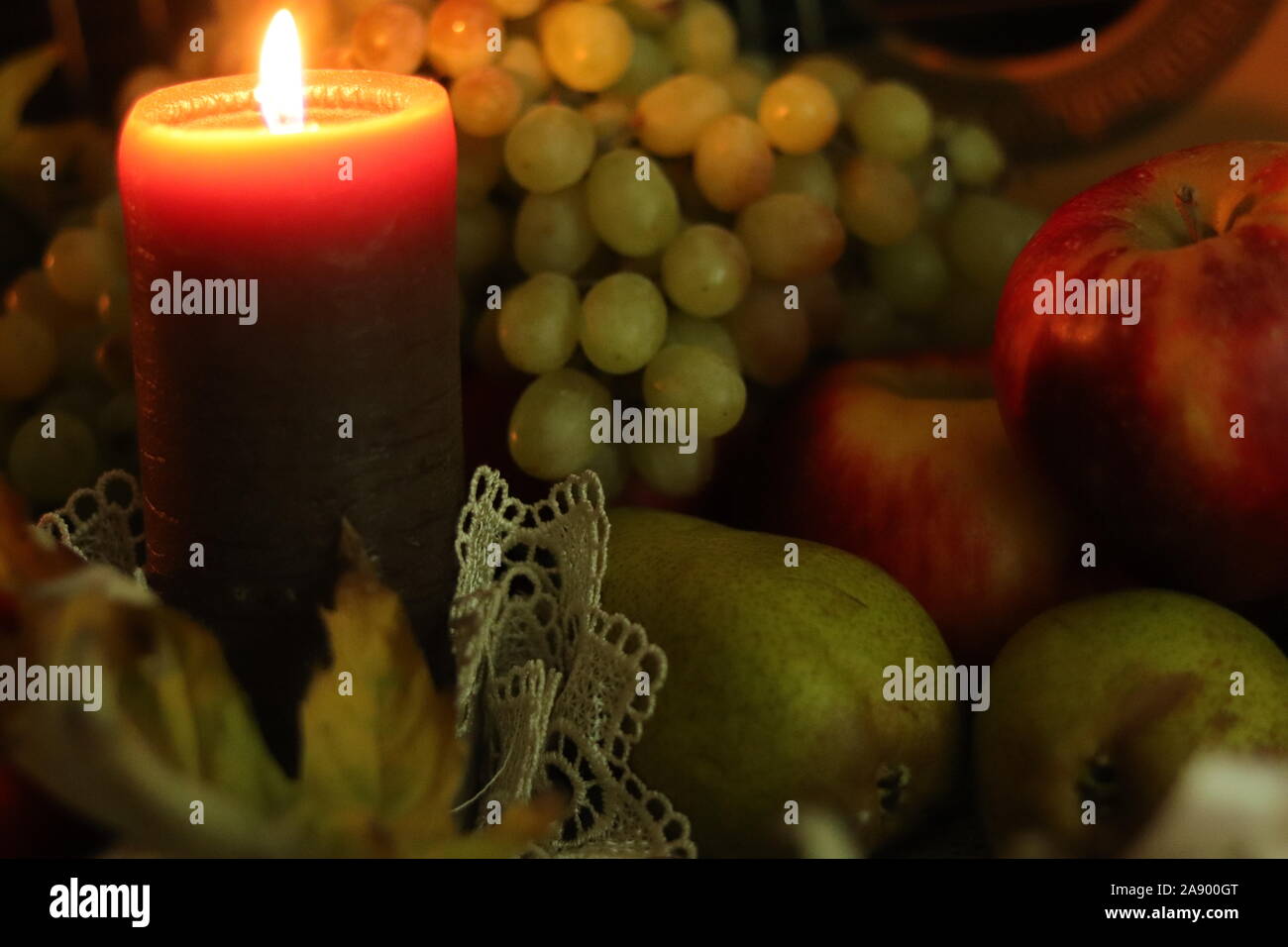 Herbst ernte noch leben. Gemütliches Haus Wärme. Kerze Flamme und Früchten Zusammensetzung: rote Äpfel, Birnen und Trauben. Stockfoto