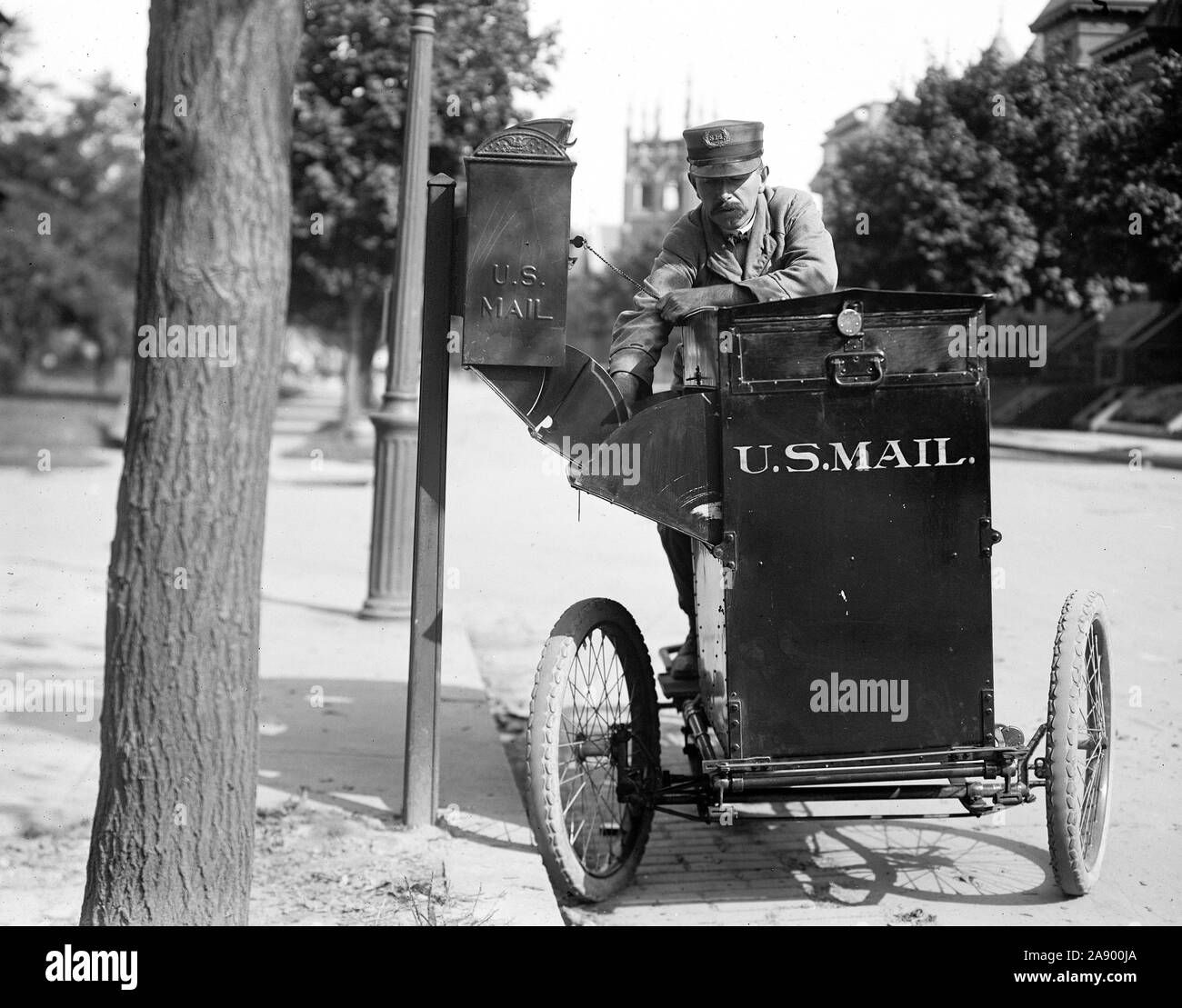 Historische United States Postal Service: Mailman auf einem Motorrad aufnehmen Mail aus einer Box Ca. 1912 Stockfoto