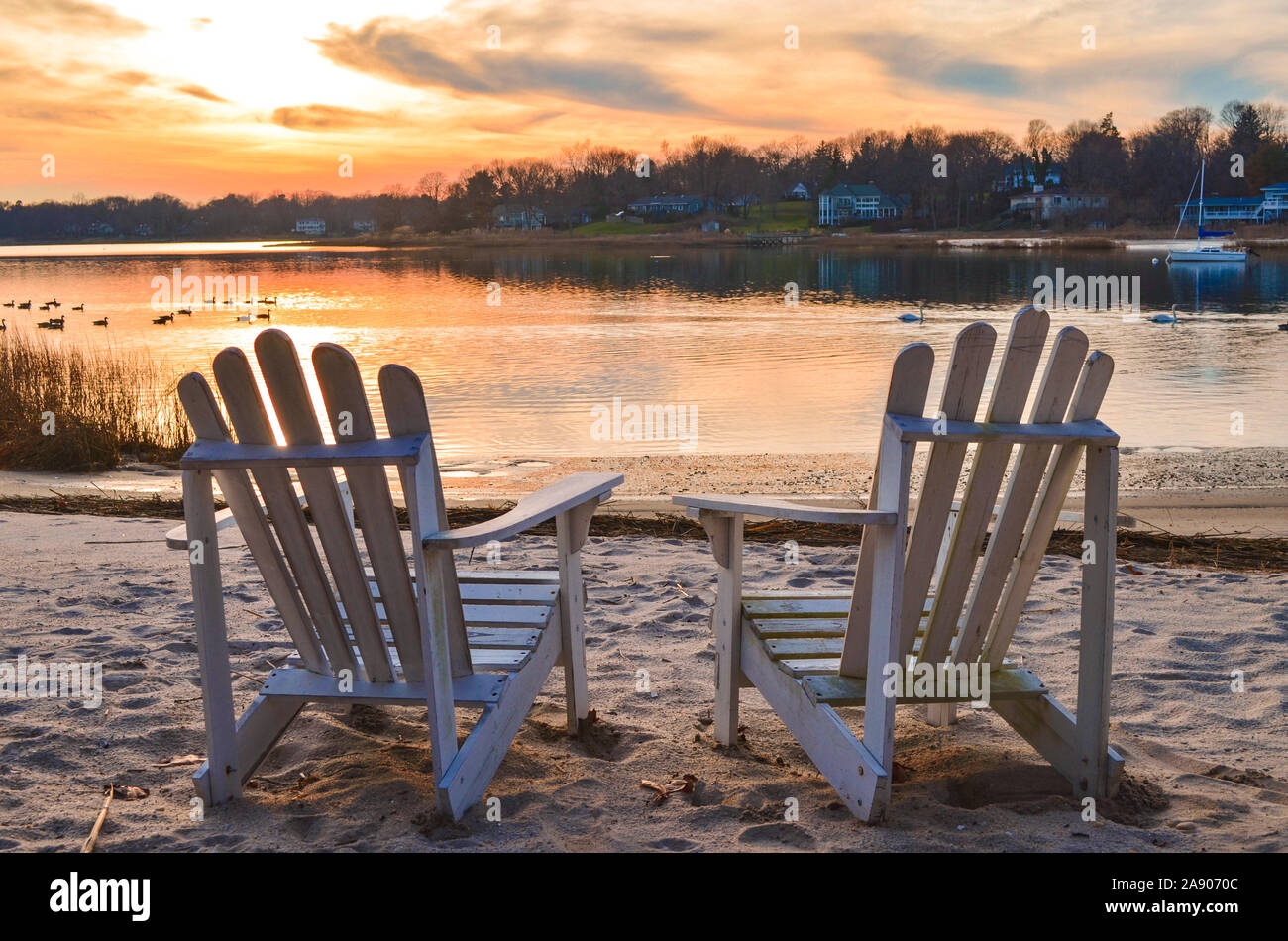 Eine mute November Sonnenuntergang sanft Farben zwei Adirondak Stühlen auf den Hafen Strand. Stockfoto