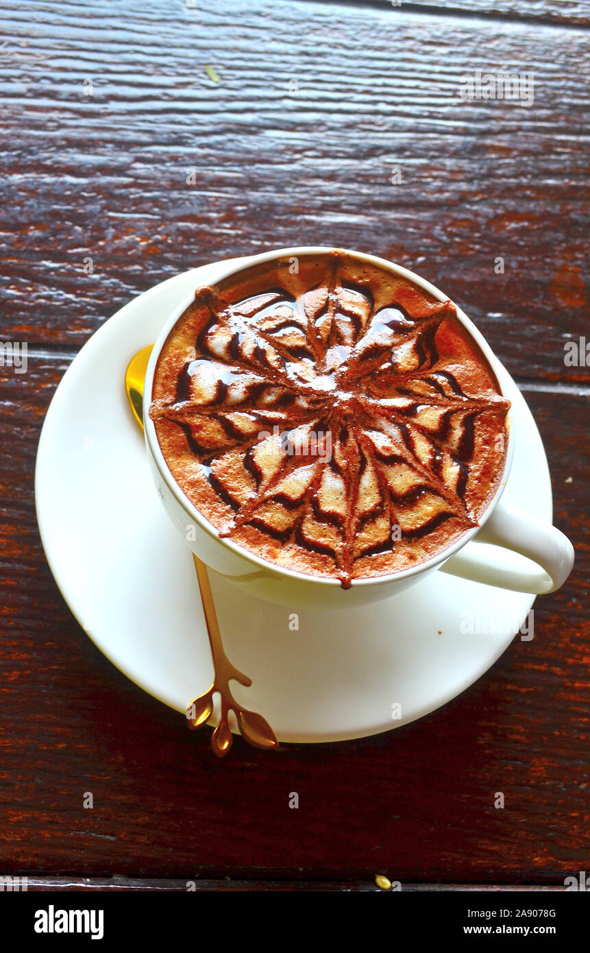 Ein Cappuccino in einem weißen Tasse auf einem weißen Untertasse mit einem schönen Muster auf der Oberseite Stockfoto