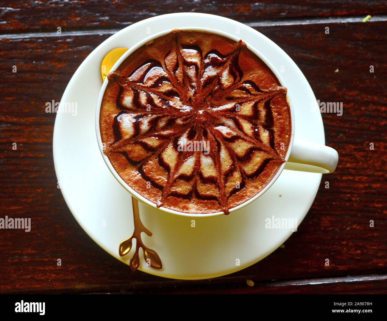 Ein Cappuccino in einem weißen Tasse auf einem weißen Untertasse mit einem schönen Muster auf der Oberseite Stockfoto