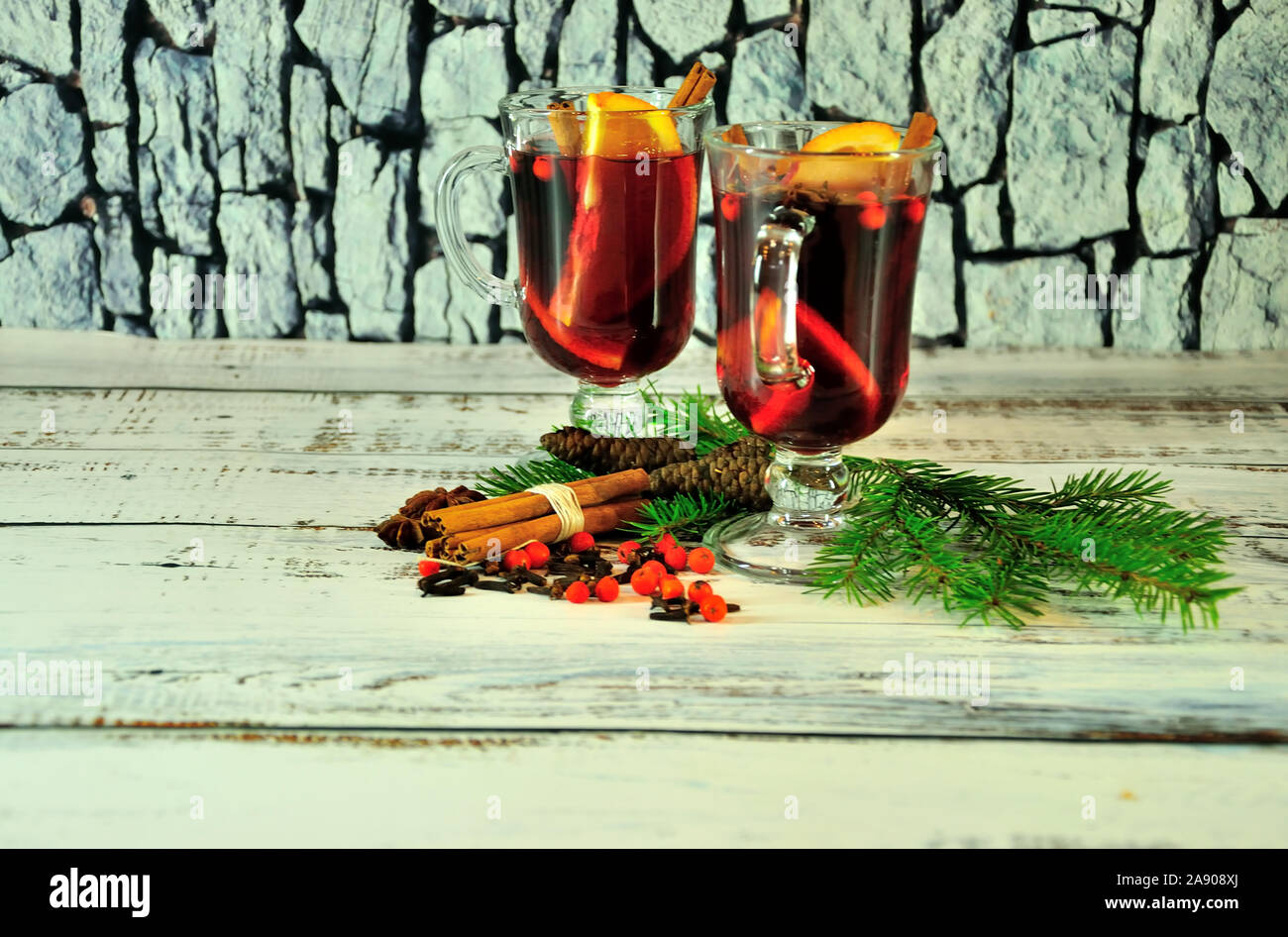 Weihnachten Zusammensetzung, zwei Gläser mit Glühwein, mit fruchtschnitten und Gewürzen, mit Tannenzapfen und Filialen eingerichtet. Close-up. Stockfoto