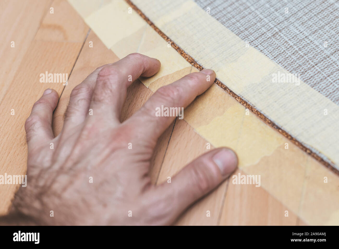 Der Arbeitnehmer überprüft, mit seiner Hand den Zustand der Kork Kompensator in der Kreuzung zwischen der Fliese und das Parkett auf dem Boden Stockfoto