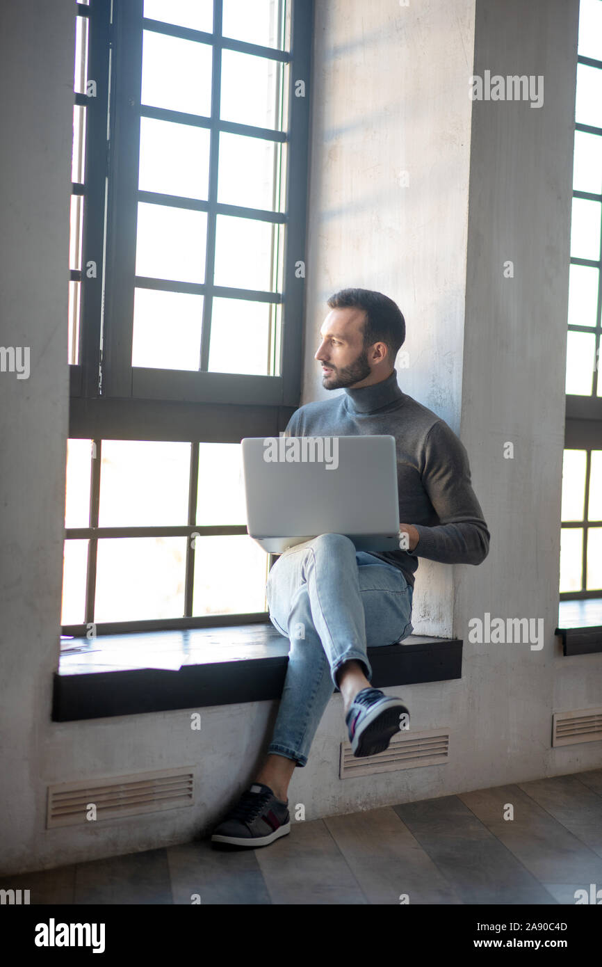 Bärtiger Mann Arbeiten von einem Remotestandort aus auf seinem Laptop Stockfoto