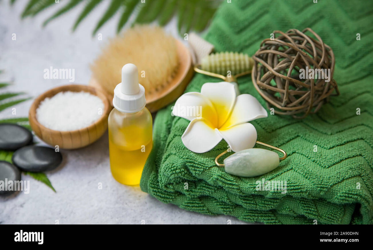 Spa Noch leben Einstellung mit Frangipani Blüten, Öl Flasche, Badesalz, Massage Steine, Handtuch und grüne Blätter, Wellness und Spa Einstellung Stockfoto