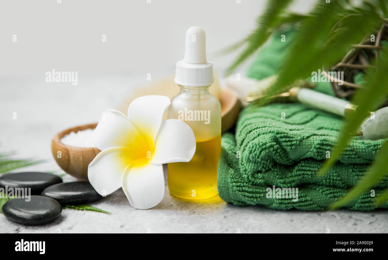 Spa Noch leben Einstellung mit Öl Flasche, frangipani Blume, Massage Steine, Handtuch und grüne Blätter, Wellness und Spa Einstellung Stockfoto