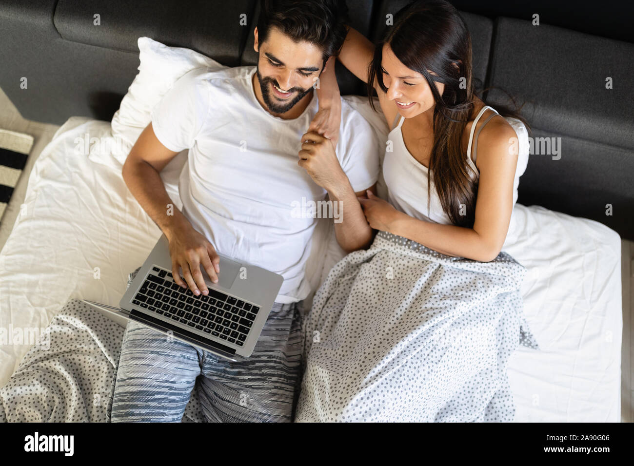 Glückliches Paar mit Laptop auf dem Bett im Schlafzimmer Stockfoto
