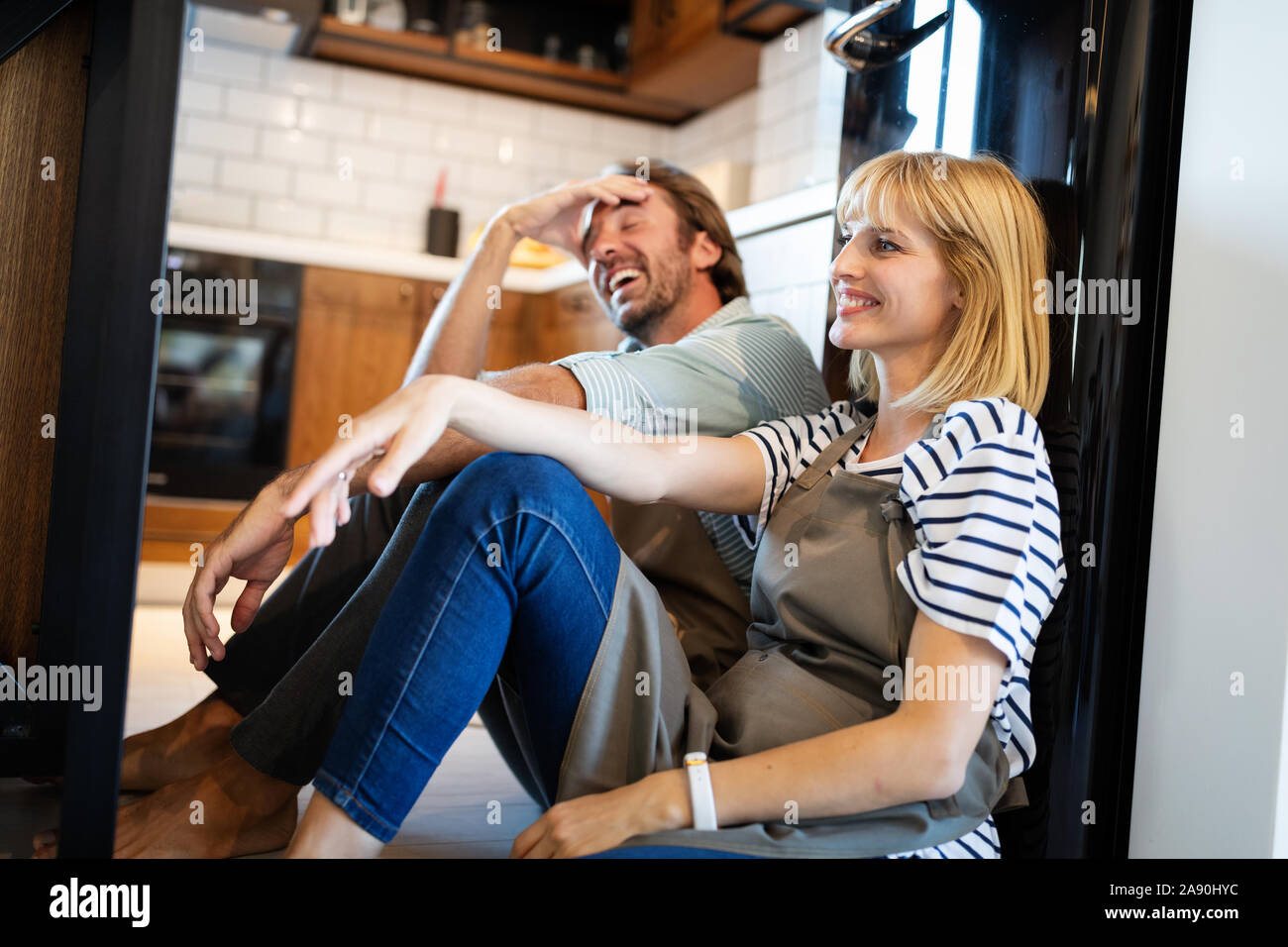 Junge glücklich müde Paar sitzt auf küchenboden nach dem Kochen Stockfoto