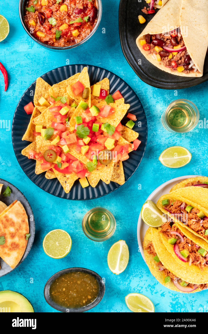 Mexikanisches Essen, viele Gerichte der Küche von Mexiko, Flach, Top Shot auf blauem Hintergrund. Nachos, Tequila, taco Shells, Burritos, Chili con Carne Stockfoto