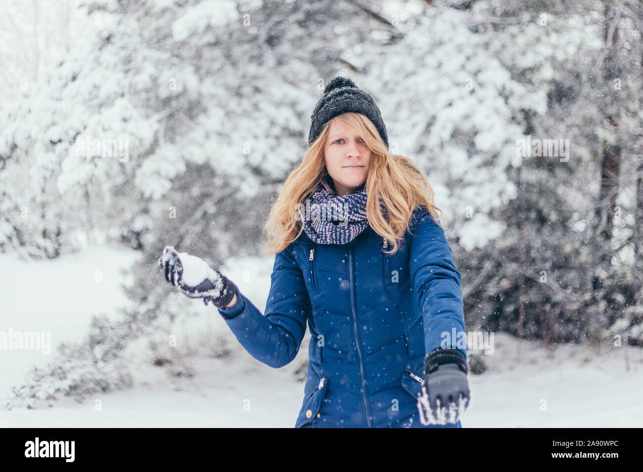 Der glückliche cute attraktives Mädchen in Wollschal genießen Winter Momente - Nähe wirft einen Schneeball Stockfoto