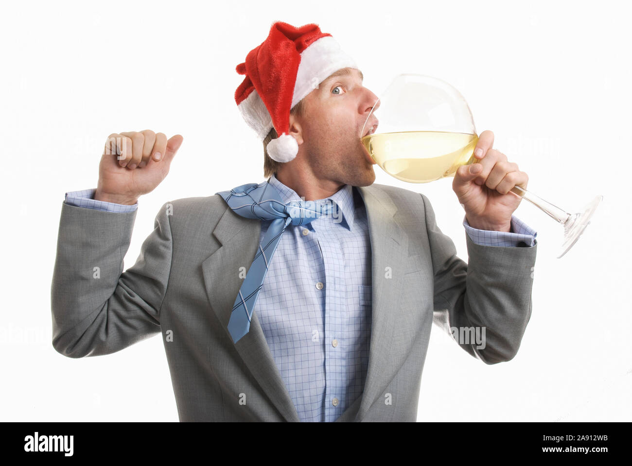 Partying Geschäftsmann in Santa hat einen grossen Schluck aus einem großen Glas Wein im Büro Holiday Party Stockfoto