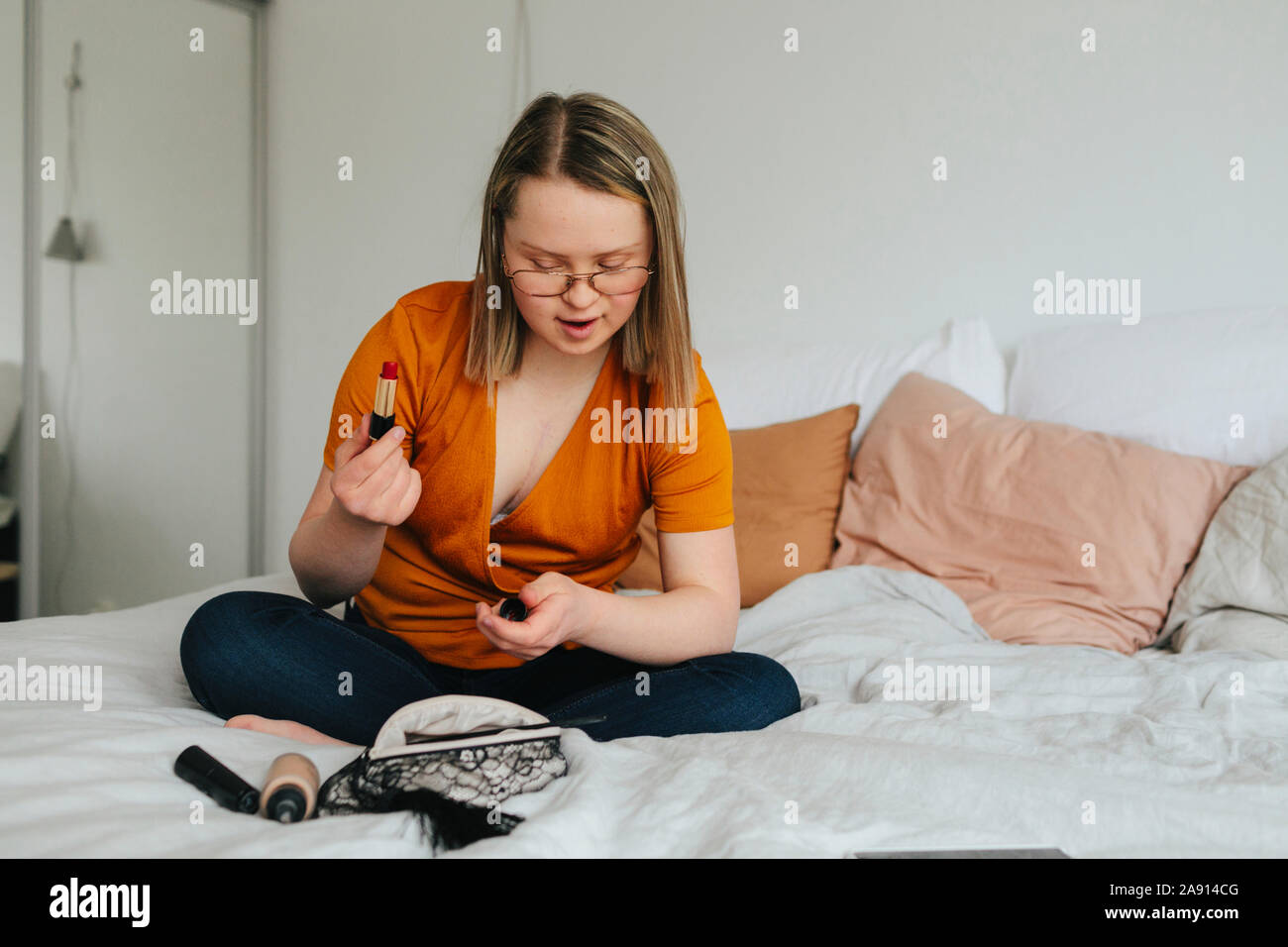 Junges Mädchen auf dem Bett Kontrolle Kosmetik Tasche Stockfoto