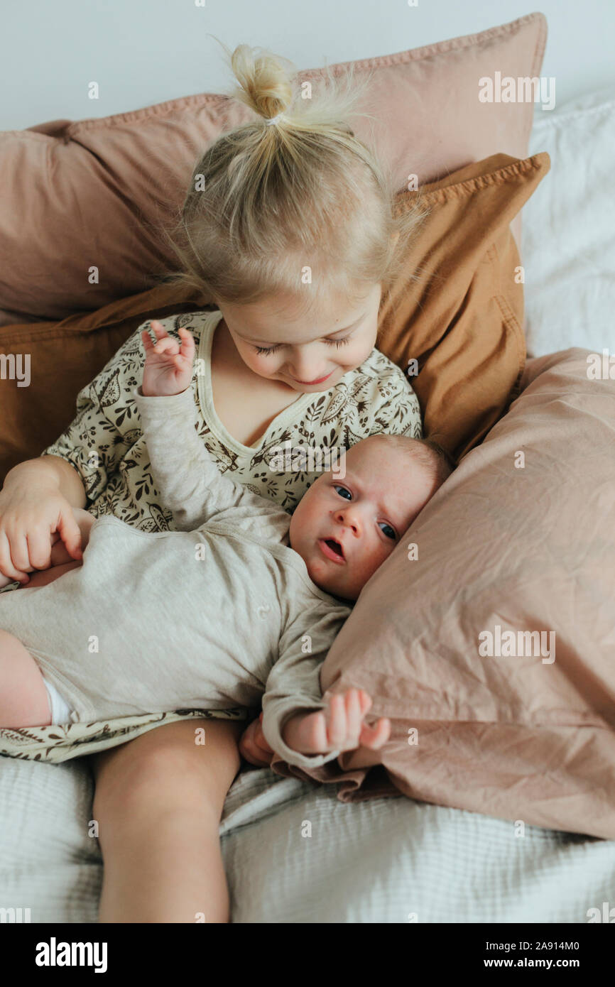 Mädchen mit Neugeborenen Geschwister auf dem Bett Stockfoto