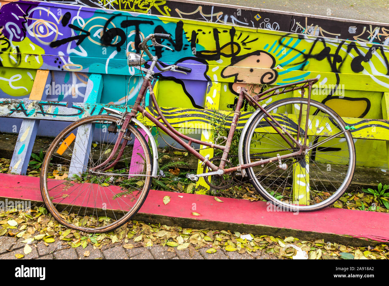 Abgebrochene Fahrrad neben bemalte Zaun - Brüssel, Belgien. Stockfoto