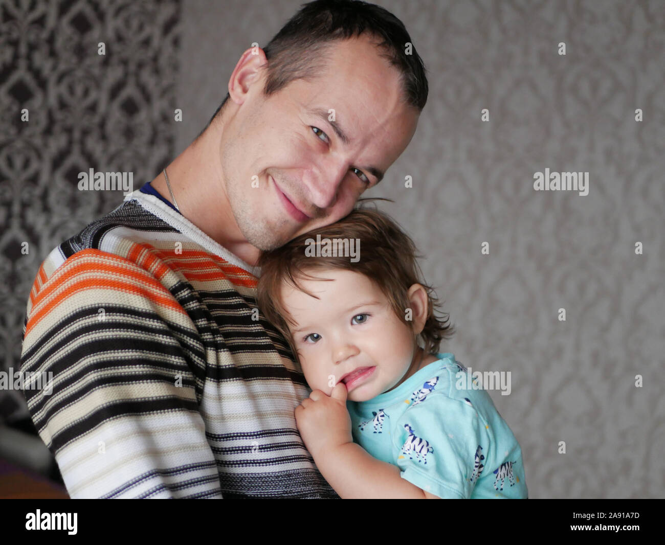 Liebevoller Vater umarmt das Kind in seine Arme. Baby 0-1 Jahr alt. Väterliche Liebe. Die Beziehung von Vater und Sohn. Ein liebevoller Vater hält, ein Kind in seine Stockfoto