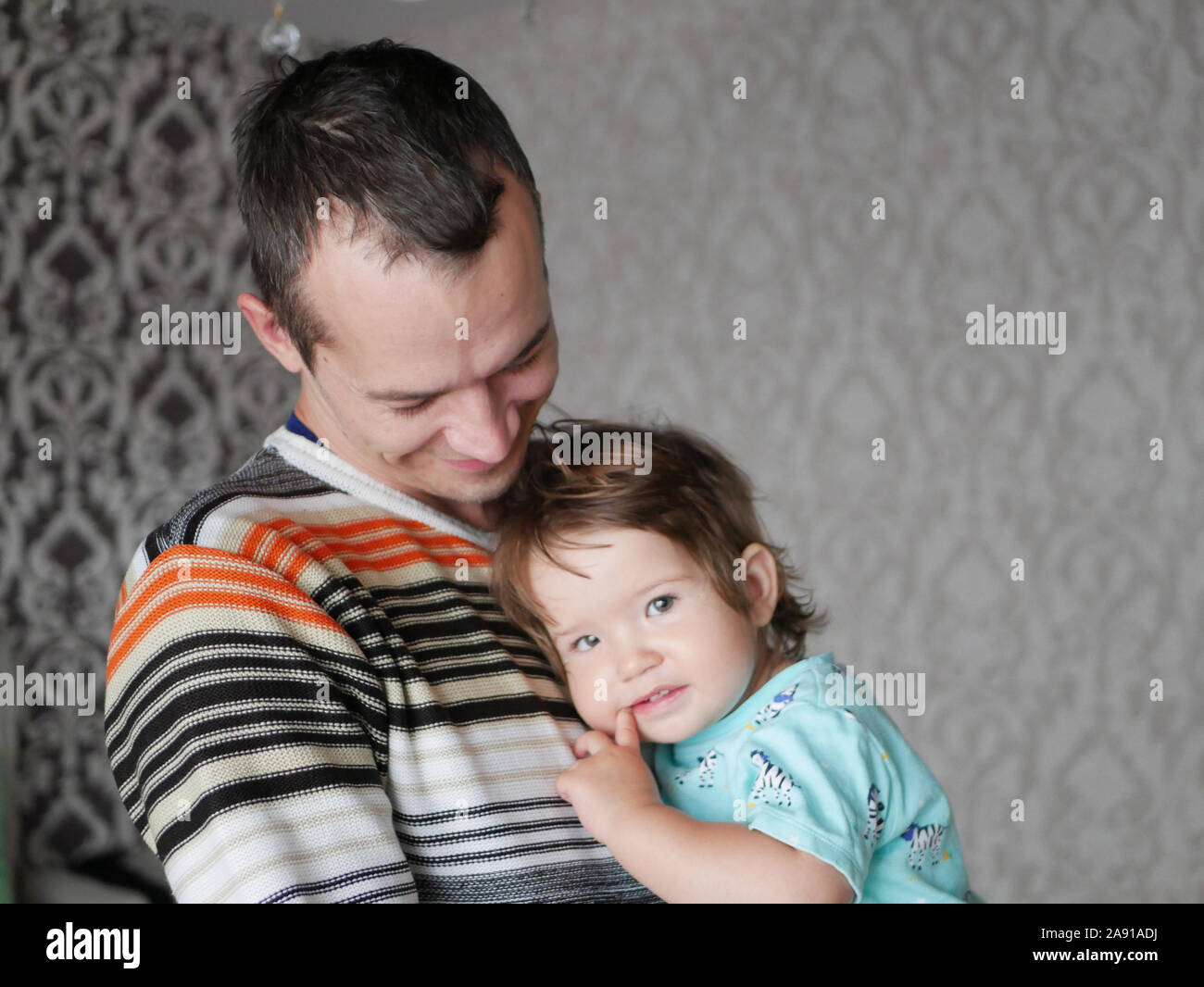 Liebevoller Vater umarmt das Kind in seine Arme. Baby 0-1 Jahr alt. Väterliche Liebe. Die Beziehung von Vater und Sohn. Ein liebevoller Vater hält, ein Kind in seine Stockfoto
