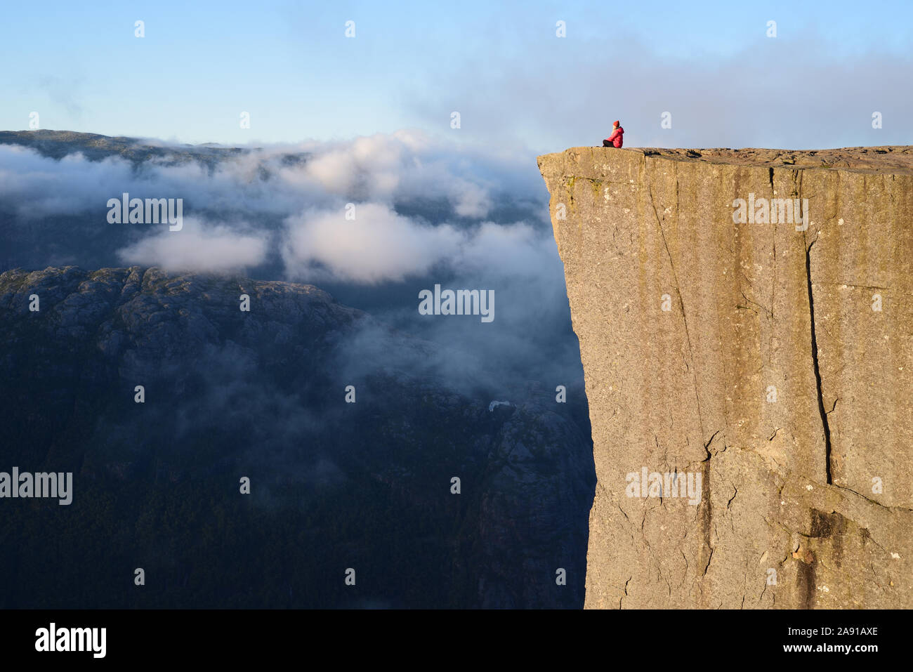 Preikestolen - amazing Rock in Norwegen. Mädchen sitzt auf einem Kliff über den Wolken. Preikestolen, der berühmtesten Sehenswürdigkeit in Ryfylke, Türme ov Stockfoto