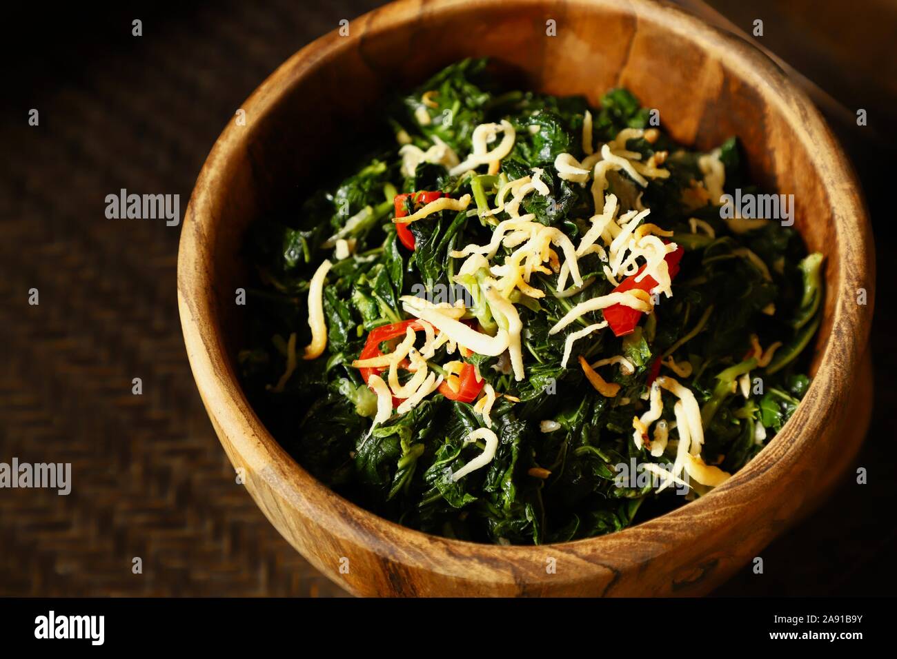 Tumis Daun Singkong. Wokgemüse 888 Blatt mit stinky Bohnen und knusprigen salte Sardellen. Stockfoto