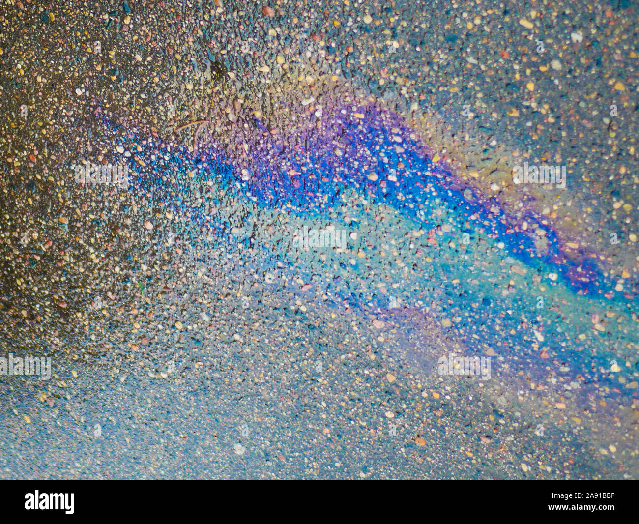 Eine Pfütze von Benzin auf dem Bürgersteig. Close-up. Benzin, auf dem nassen Asphalt zugespielt hatte. Bunte Benzin, auf dem nassen Asphalt ins Sekundaersystem gelangt Stockfoto