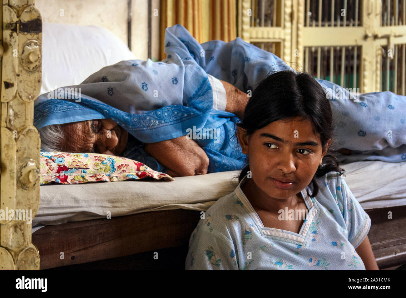Pushkar, Rajasthan, Indien: Eine ältere Indianerin schläft auf dem Bett, während ein Mädchen neben ihr sitzt. Stockfoto